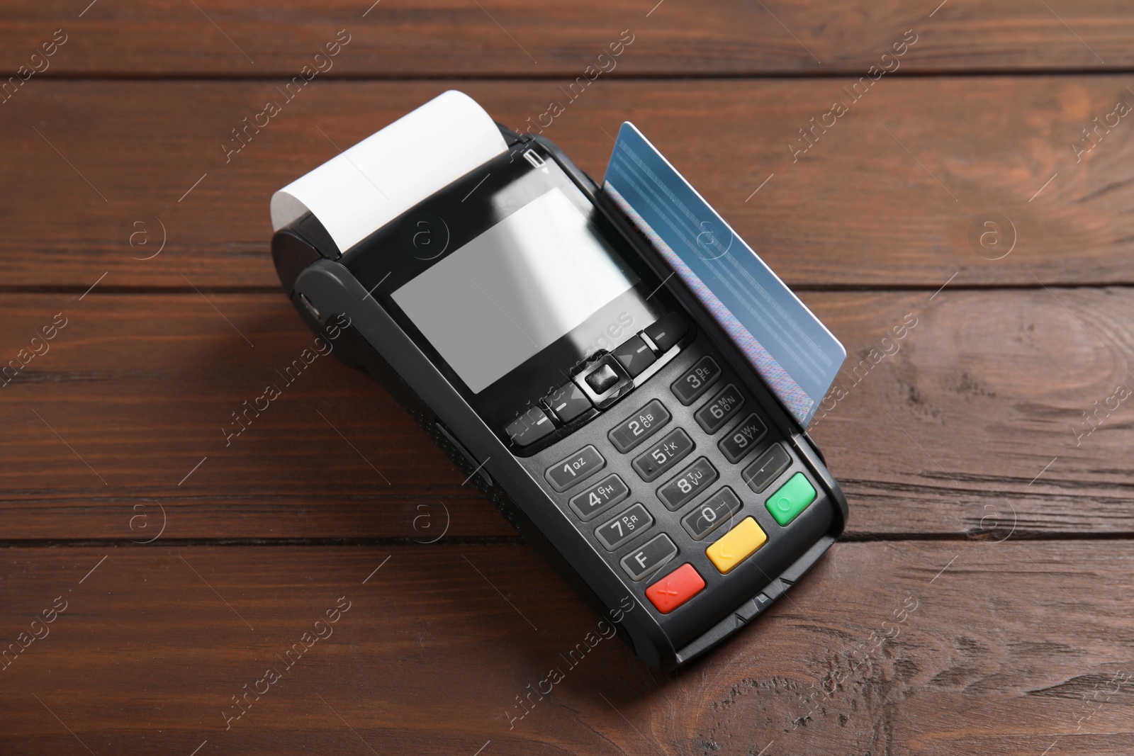 Photo of Modern payment terminal with credit card on wooden background