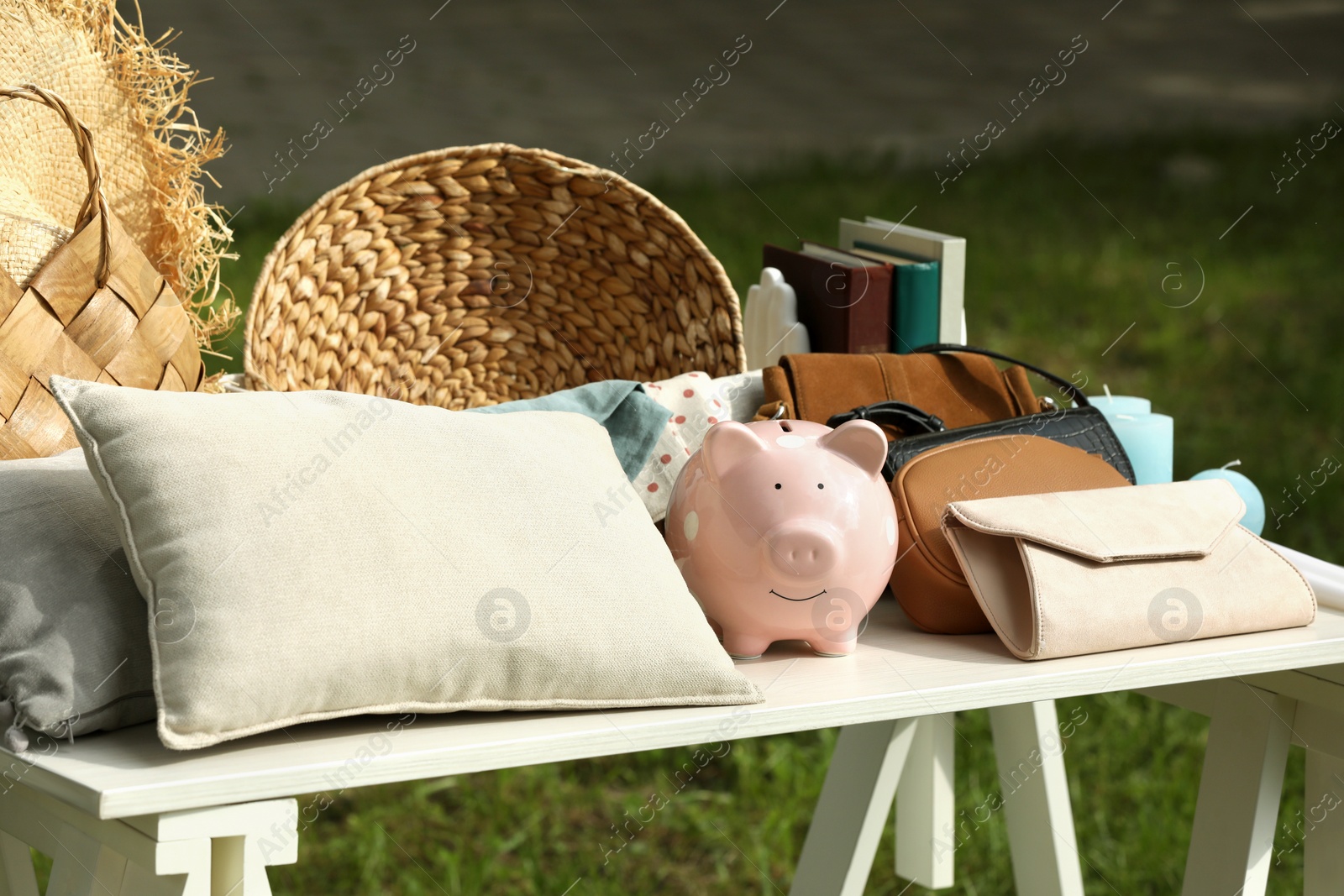 Photo of Many different items on white table outdoors. Garage sale