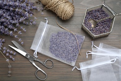Photo of Scented sachet with dried lavender flowers, scissors and twine on wooden table, flat lay