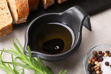 Saucepan of organic balsamic vinegar with oil, spices and bread slices on beige table, closeup