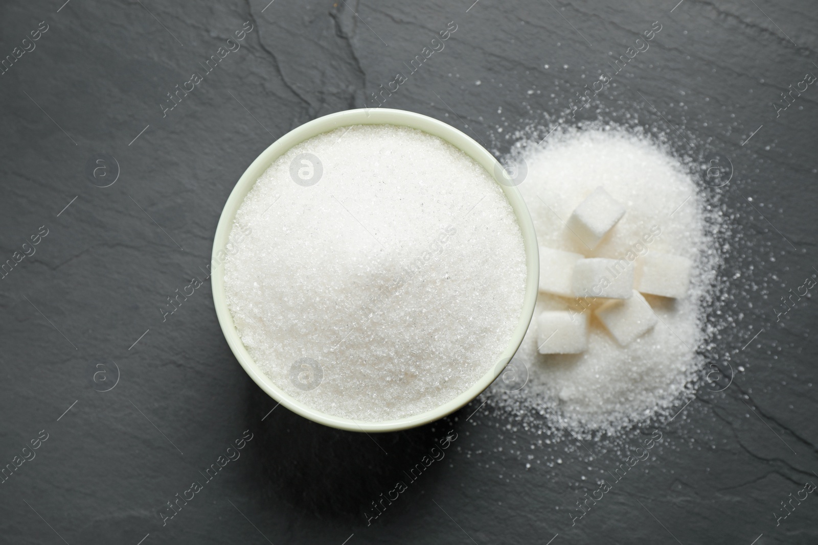 Photo of Flat lay composition with granulated sugar on dark table