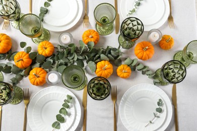 Beautiful autumn table setting. Plates, cutlery, glasses, pumpkins and floral decor, flat lay