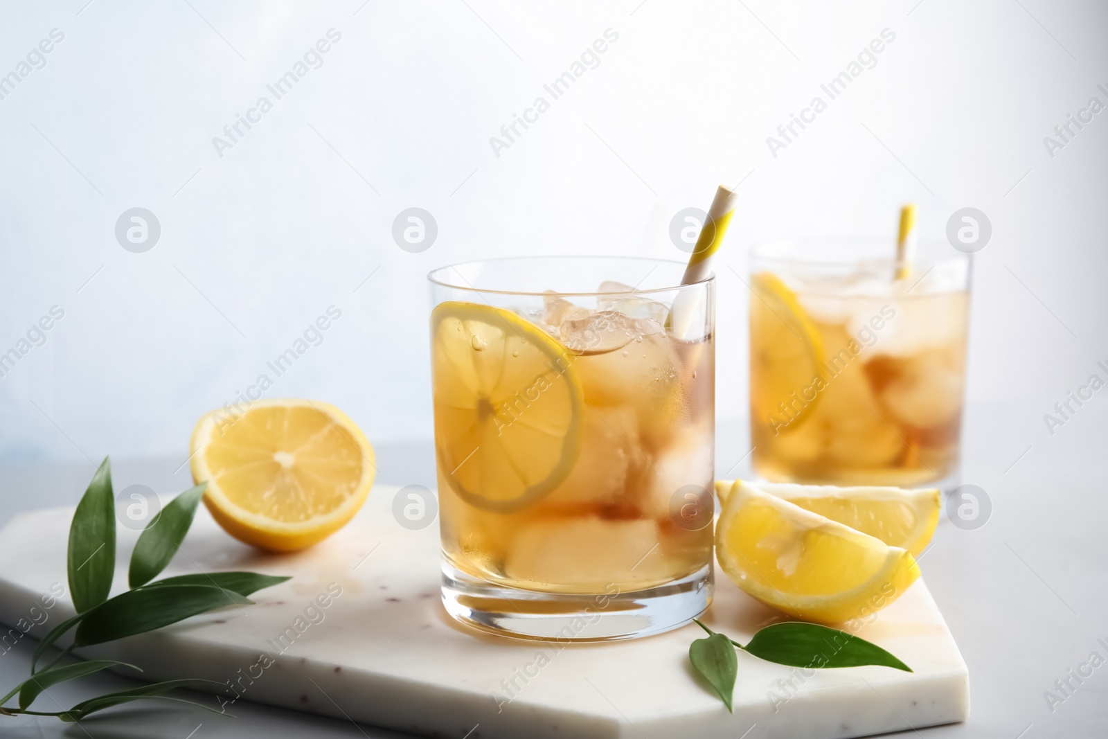 Photo of Glasses of lemonade with ice cubes on table against light background. Space for text