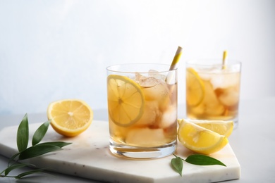 Glasses of lemonade with ice cubes on table against light background. Space for text