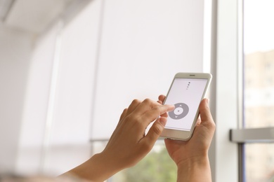 Photo of Woman using smart home application on phone to control window blinds indoors, closeup. Space for text