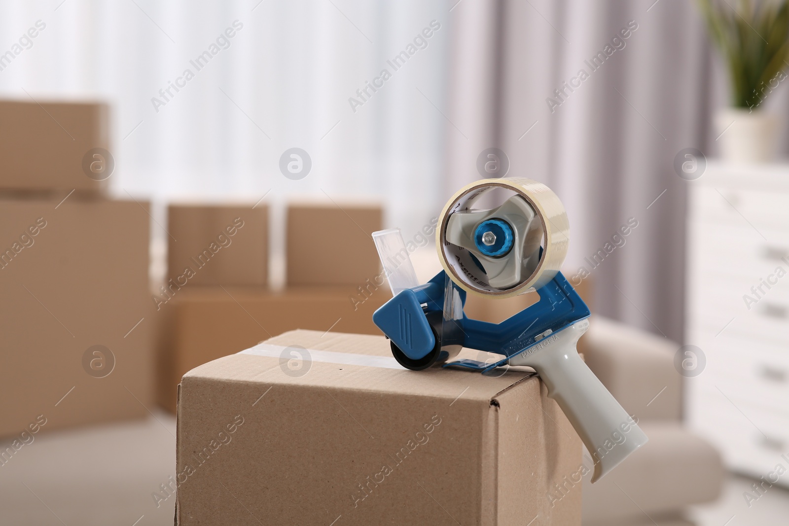 Photo of Dispenser with roll of adhesive tape on box indoors. Space for text