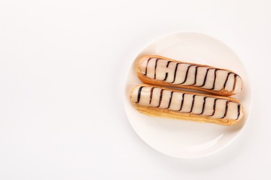 Photo of Delicious eclairs covered with glaze on white background, top view