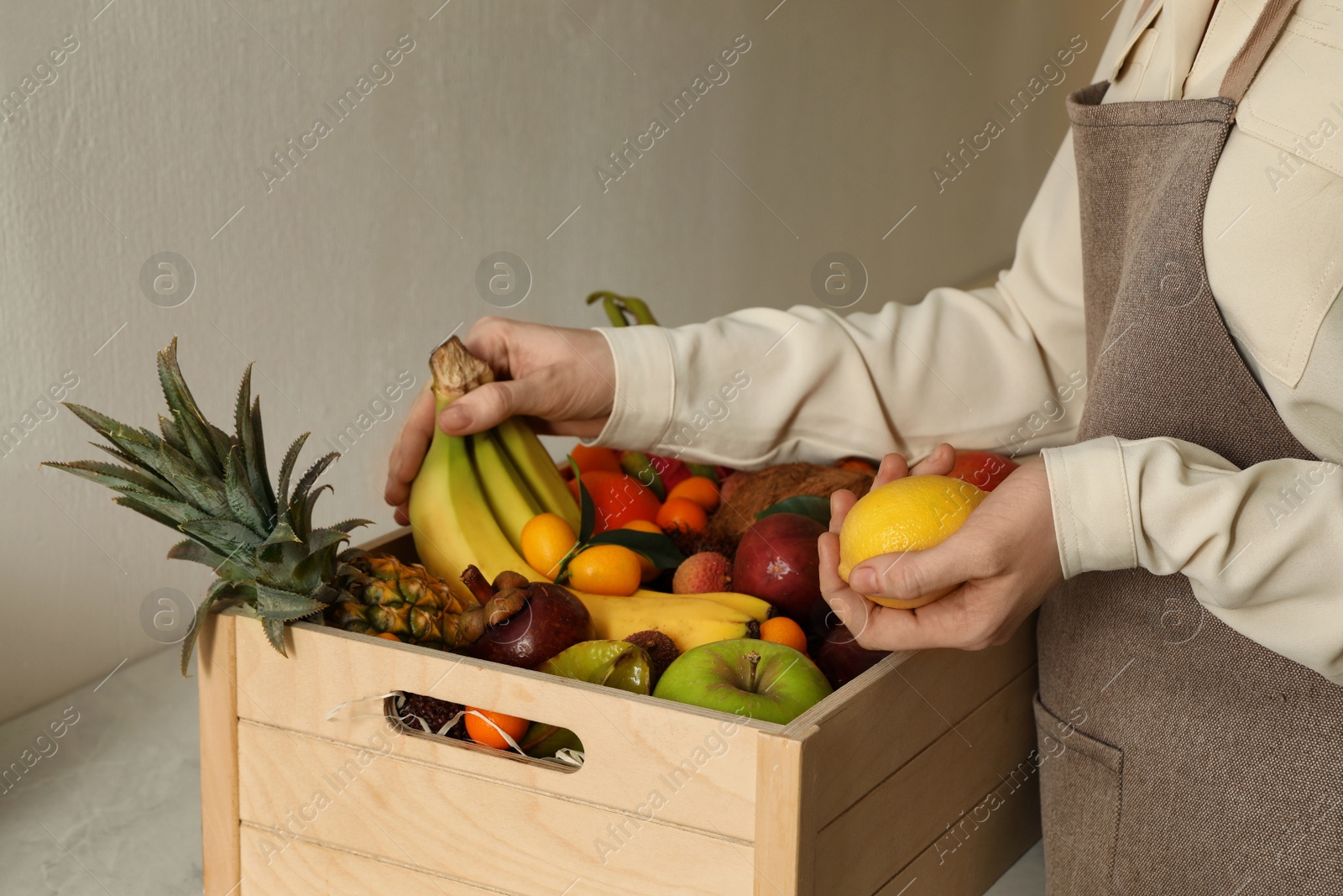 Photo of Woman with assortment of exotic fruits at table in kitchen, closeup