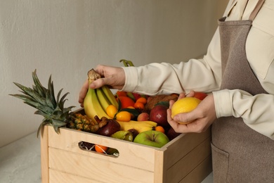 Woman with assortment of exotic fruits at table in kitchen, closeup