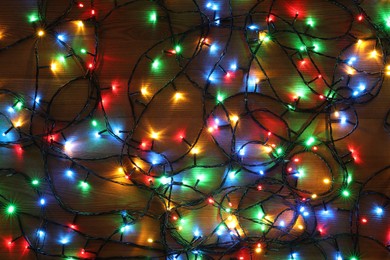 Photo of Colorful Christmas lights on wooden table, top view