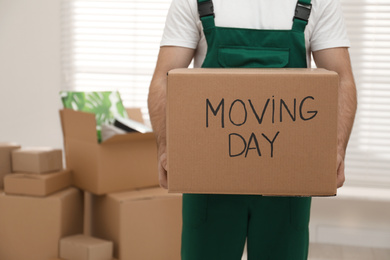 Photo of Man holding cardboard box with words MOVING DAY in room, closeup