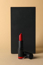 Beautiful glossy red lipstick on beige background