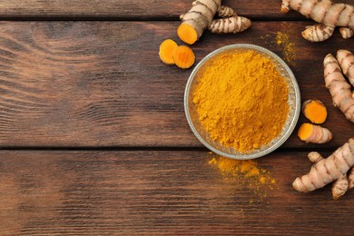 Plate with aromatic turmeric powder and cut roots on wooden table, flat lay. Space for text