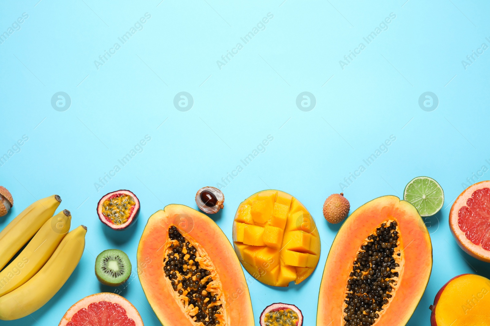 Photo of Fresh ripe papaya and other fruits on light blue background, flat lay. Space for text