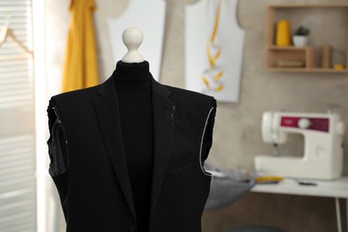 Photo of Mannequin with unfinished suit jacket in tailor shop. Space for text