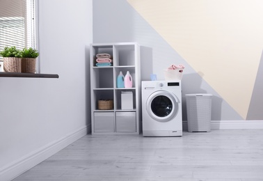 Modern washing machine in laundry room interior