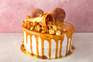 Delicious homemade cake with caramel sauce and popcorn on table