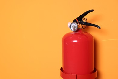 Red fire extinguisher on orange background. Space for text