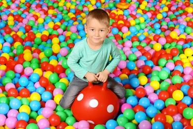 Cute child playing in ball pit indoors