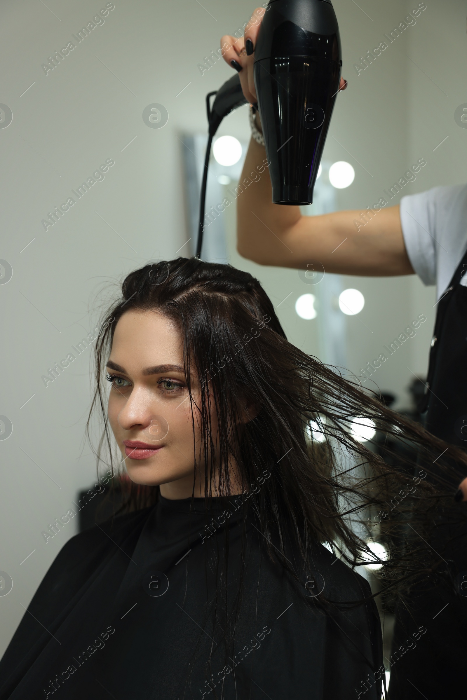 Photo of Hairdresser drying woman's hair in beauty salon