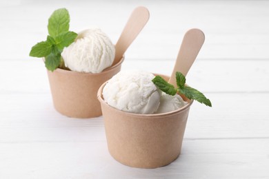 Photo of Delicious vanilla ice cream and mint on white wooden table, closeup