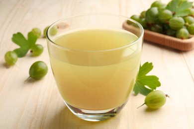 Tasty gooseberry juice in glass on wooden table, closeup