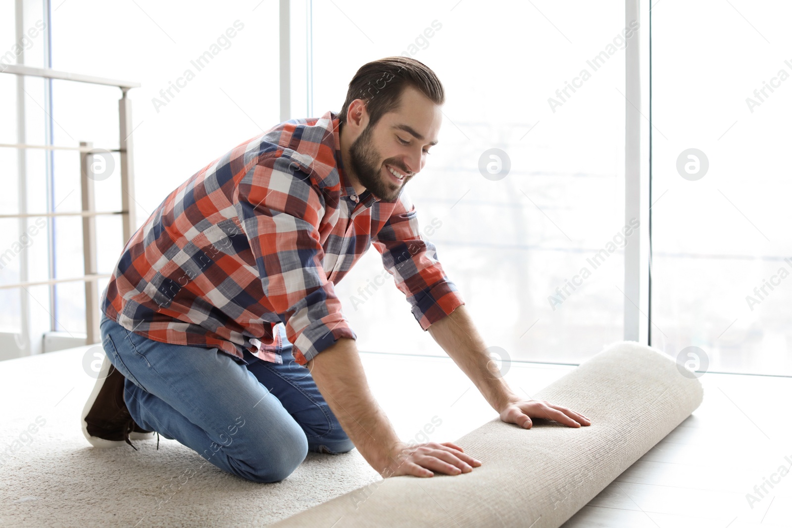 Photo of Man rolling out new carpet flooring in room