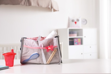 Maternity bag with baby accessories on table indoors. Space for text