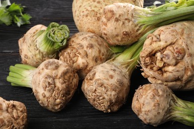 Photo of Fresh raw celery roots black wooden table