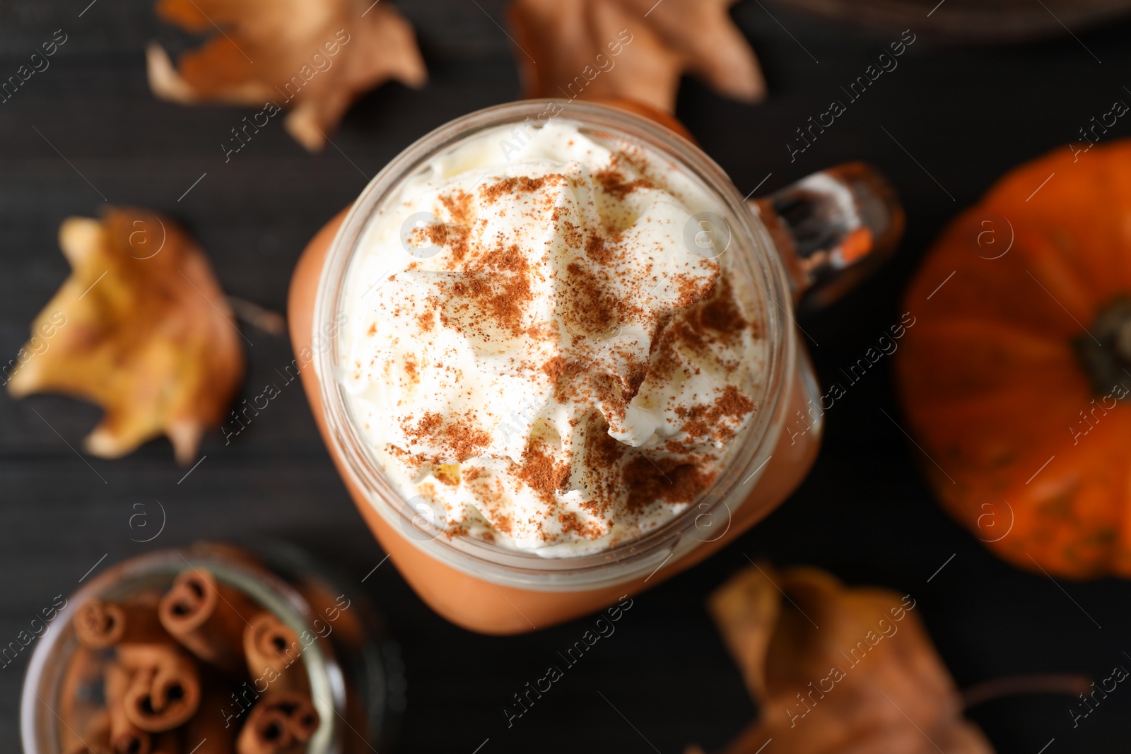 Photo of Delicious pumpkin latte on black table, top view