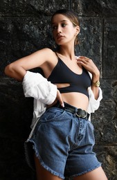 Photo of Beautiful young woman near dark stone wall