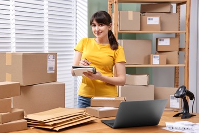 Parcel packing. Post office worker writing notes indoors