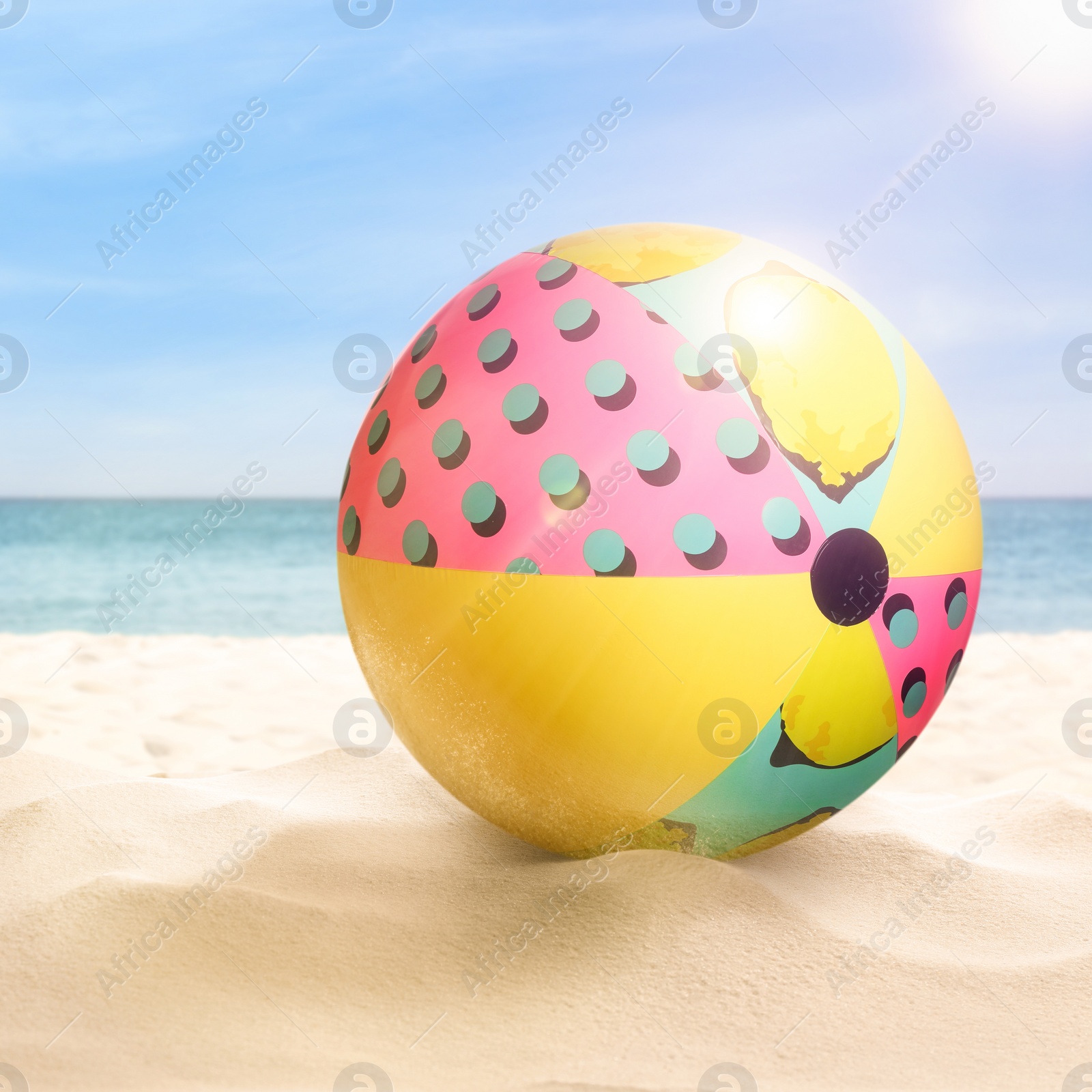 Image of Colorful beach ball on sandy coast near sea