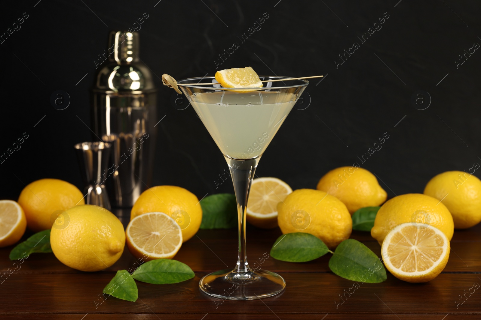 Photo of Lemon Martini cocktail, shaker and fresh fruits on wooden table