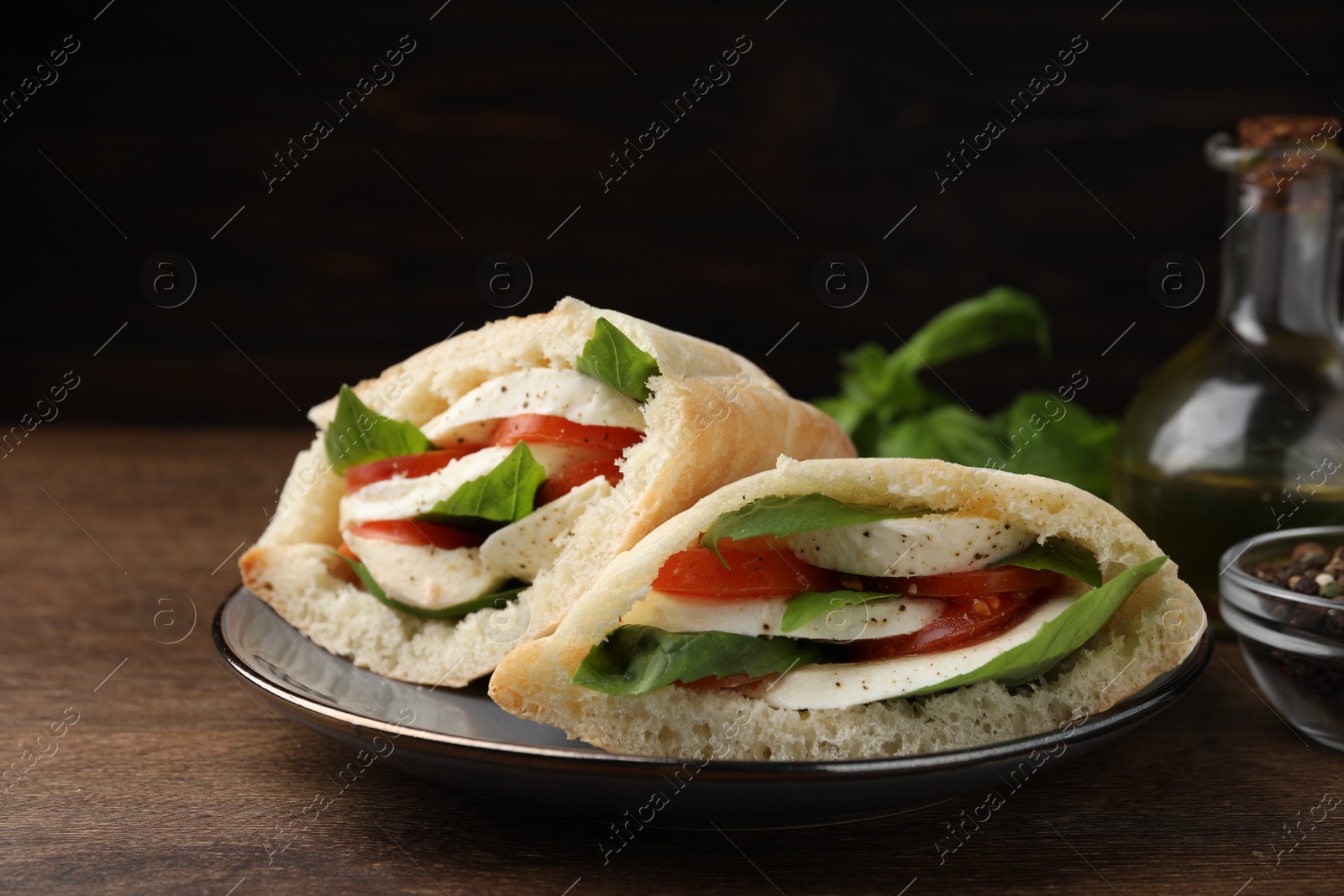 Photo of Delicious pita sandwiches with mozzarella, tomatoes and basil on wooden table