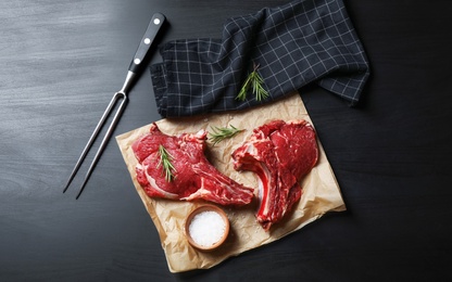 Flat lay composition with fresh meat on black wooden table