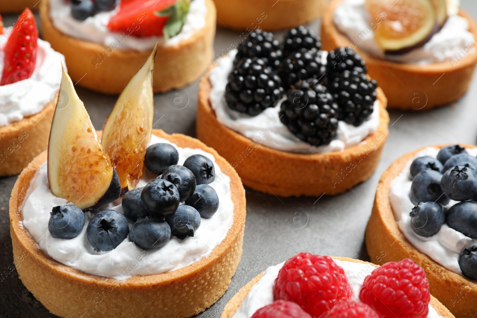 Photo of Many different berry tarts on table, closeup. Delicious pastries