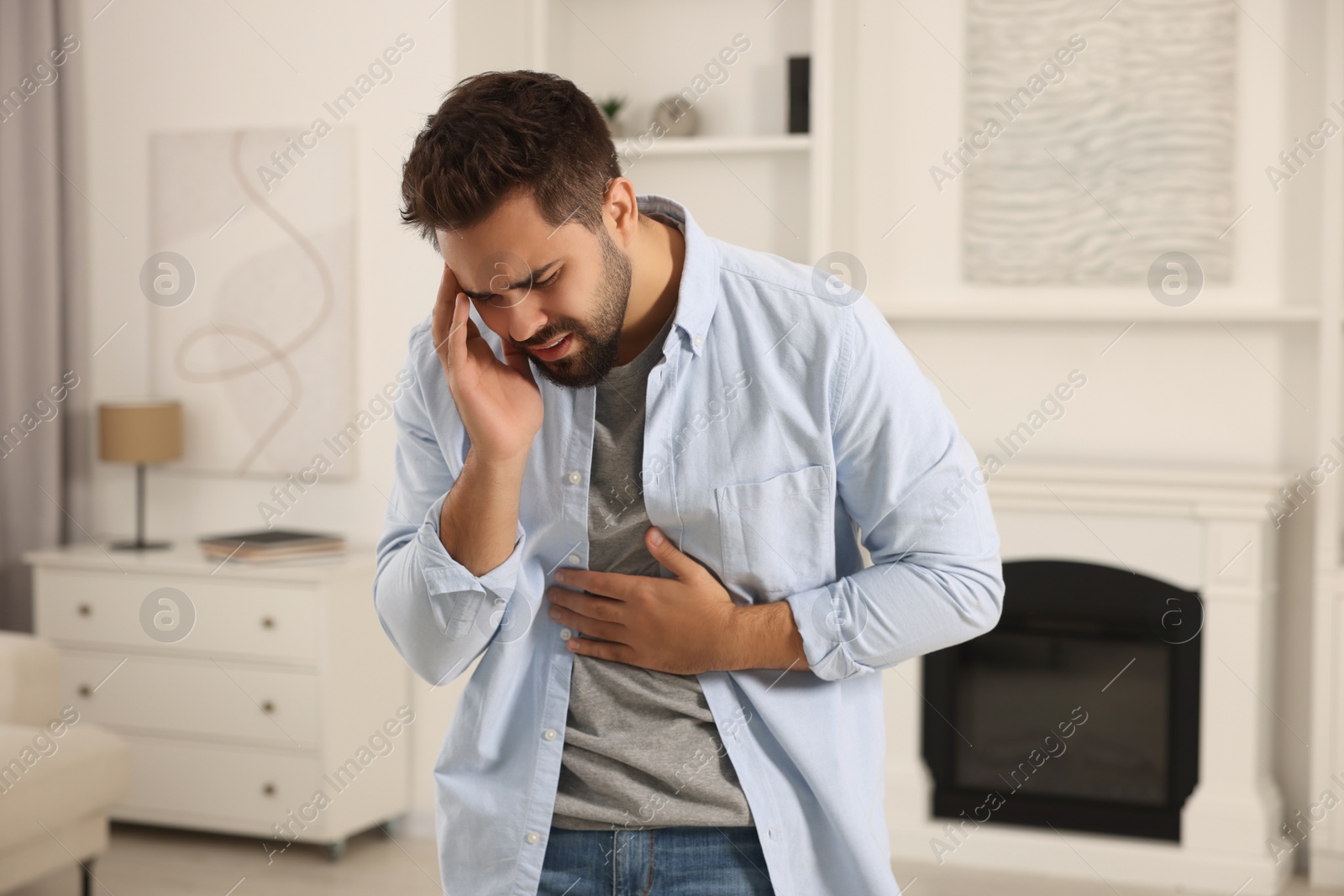 Photo of Young man suffering from stomach pain indoors