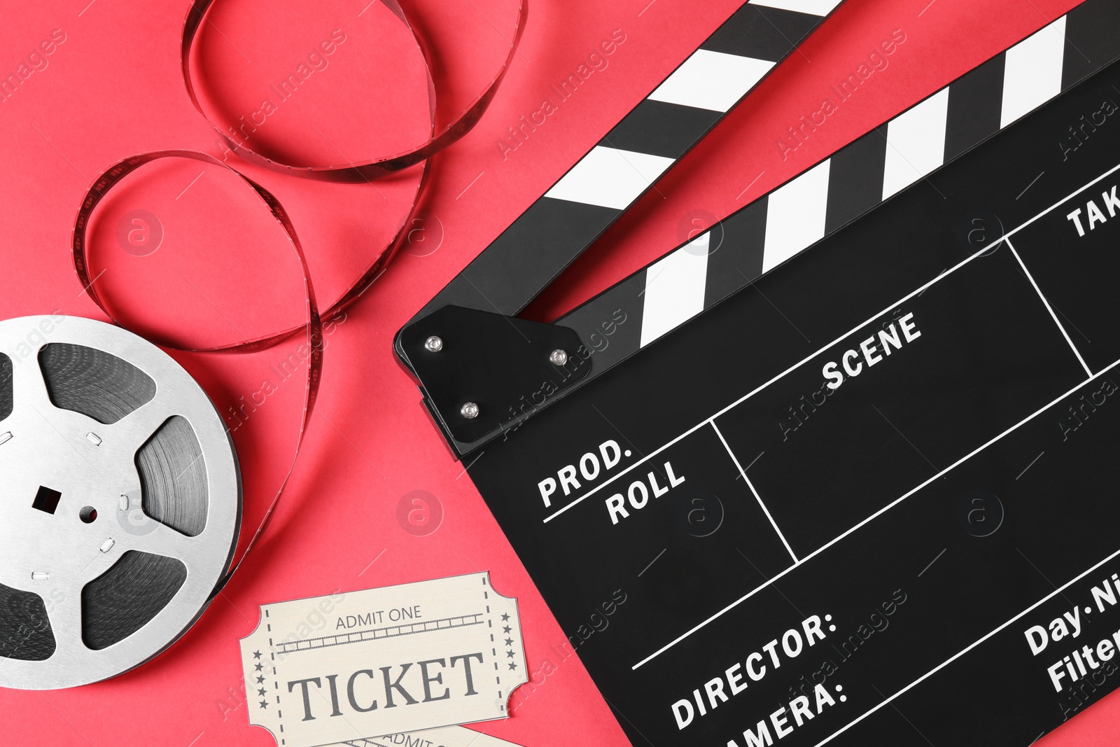 Photo of Clapperboard, movie tickets and film reel on red background, flat lay