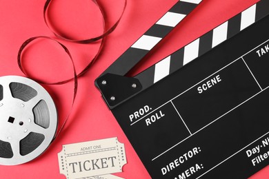 Clapperboard, movie tickets and film reel on red background, flat lay