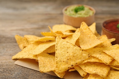 Photo of Mexican nacho chips on wooden table, closeup