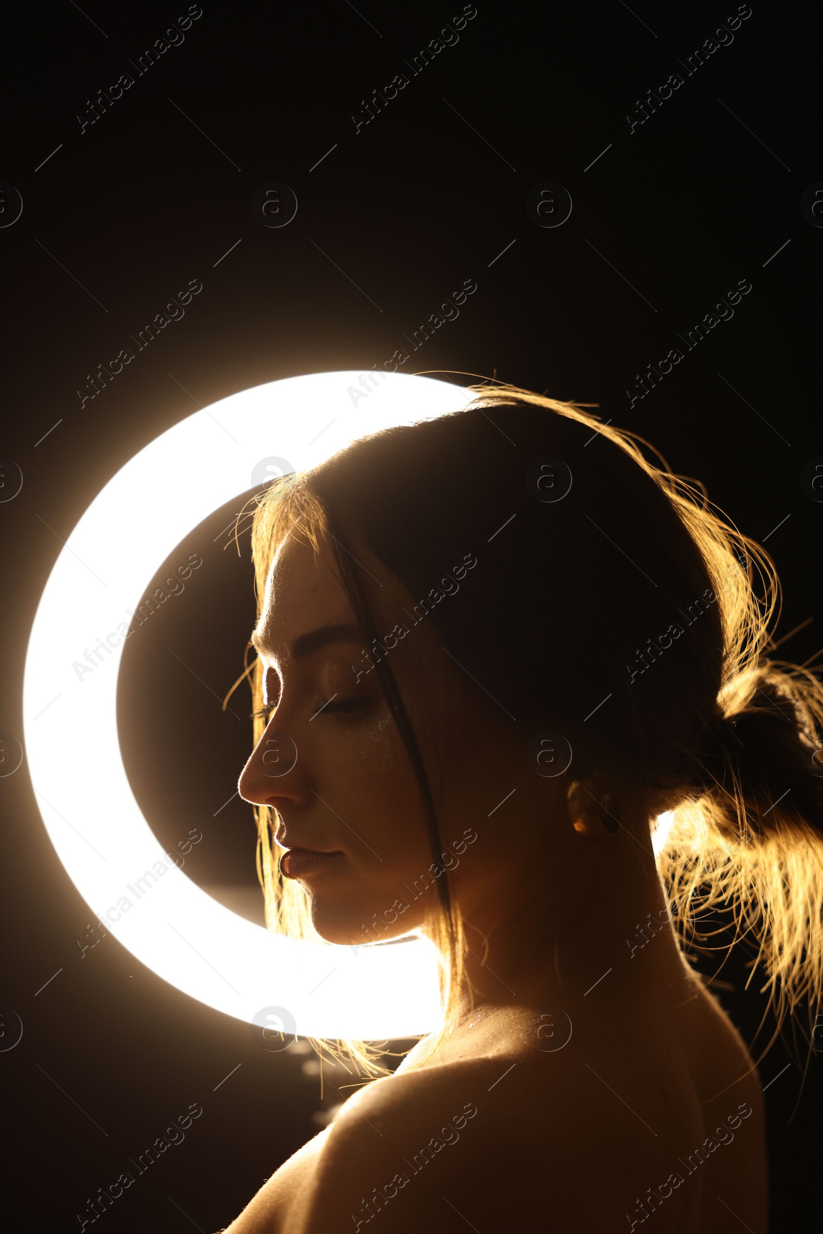 Photo of Beautiful woman and ring lamp in darkness