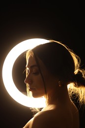 Photo of Beautiful woman and ring lamp in darkness