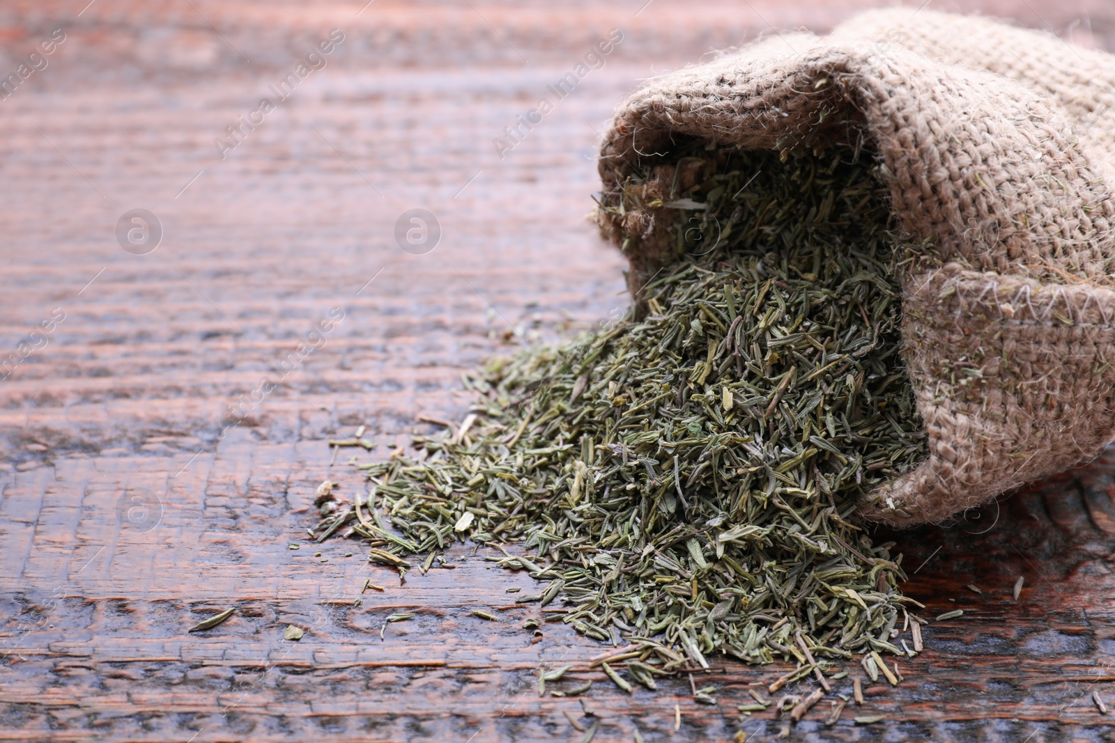 Photo of Sack with dried thyme on wooden table, closeup. Space for text