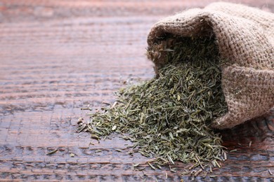 Photo of Sack with dried thyme on wooden table, closeup. Space for text