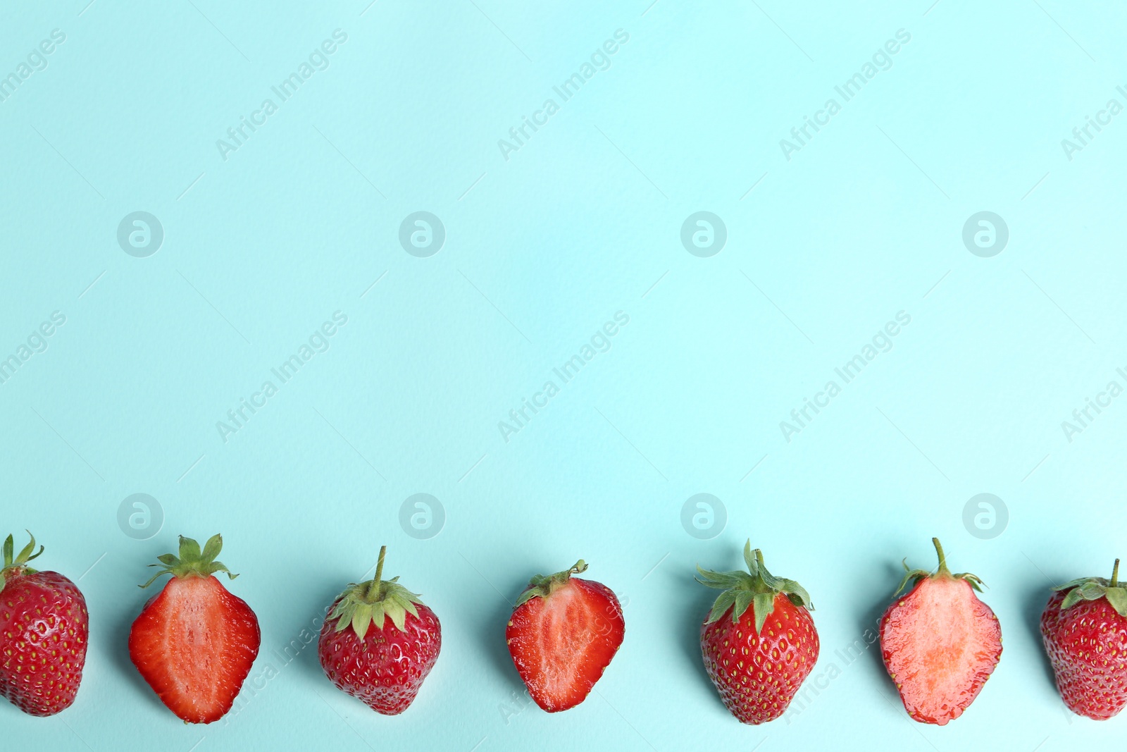 Photo of Tasty ripe strawberries on light blue background, flat lay. Space for text