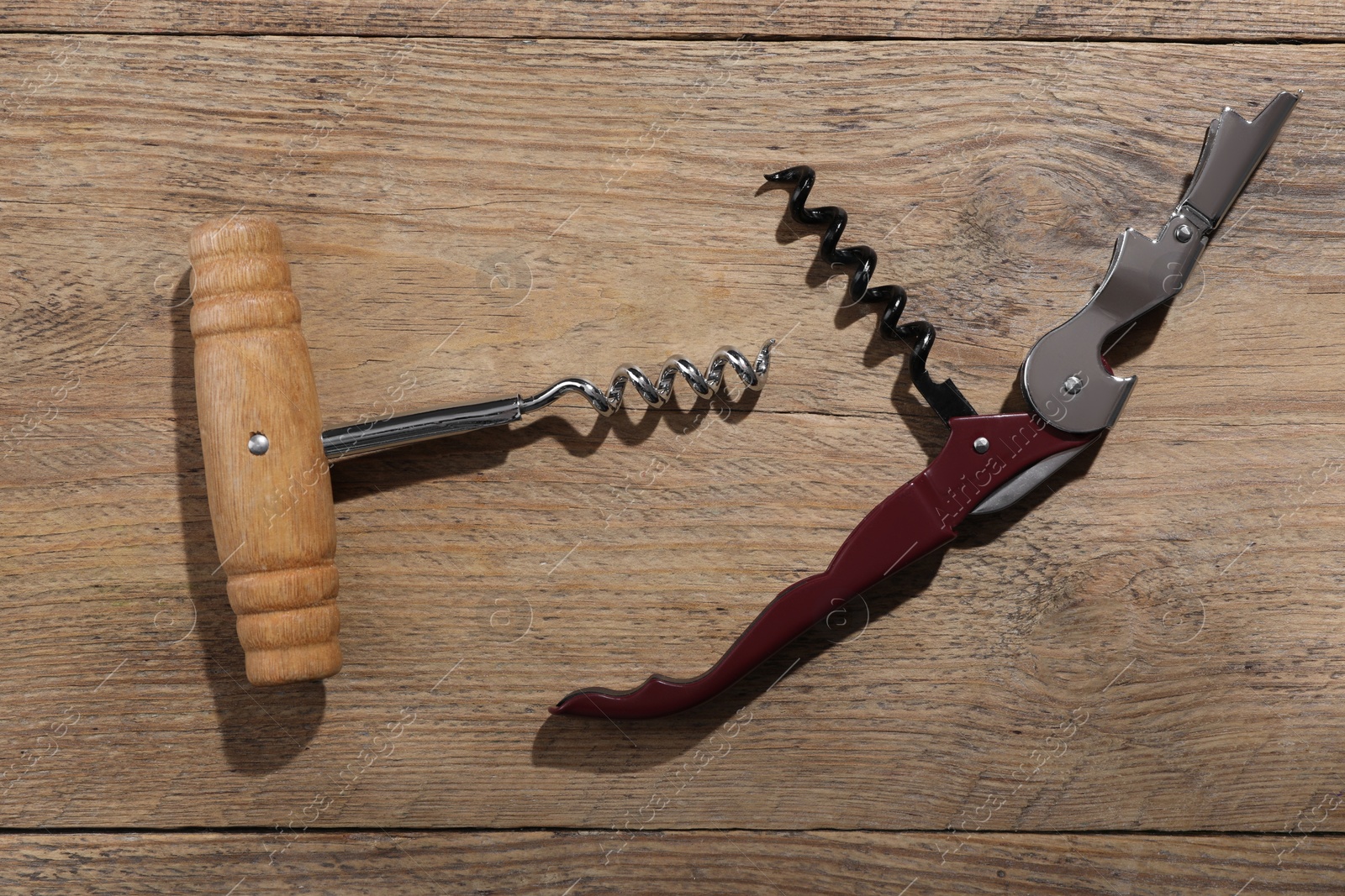 Photo of Different corkscrews on wooden table, flat lay