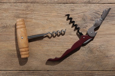 Different corkscrews on wooden table, flat lay