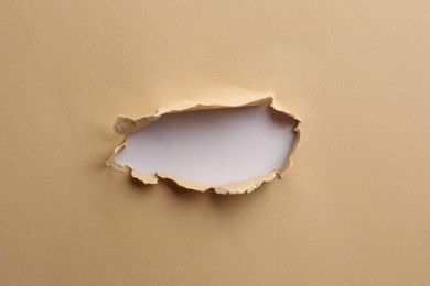 Hole in light beige paper on white background