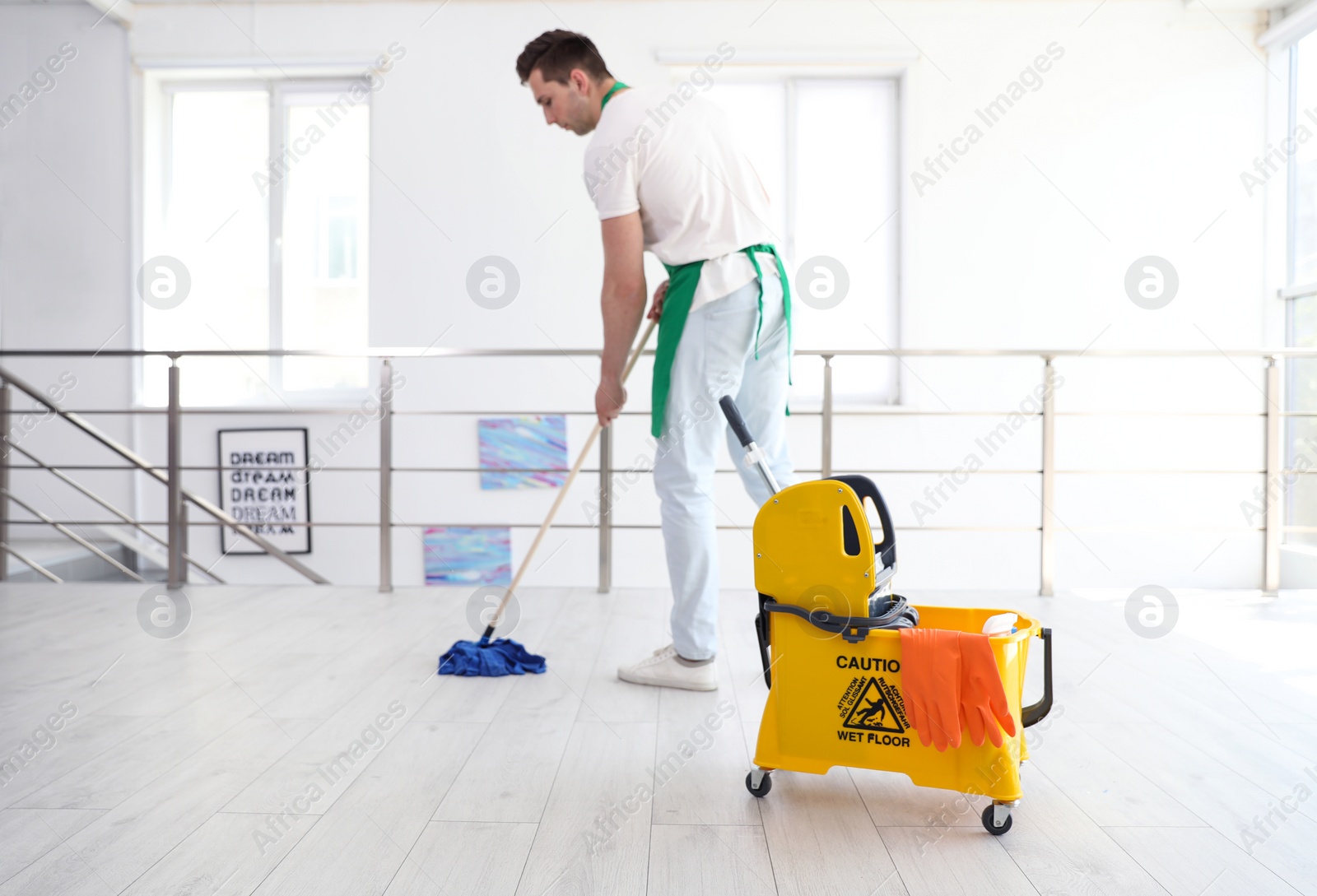 Photo of Young man with mop cleaning floor, indoors